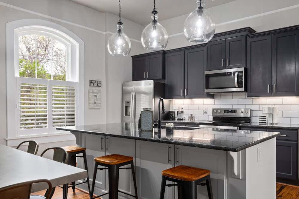Black kitchen cabinets are seen in an otherwise white kitchen