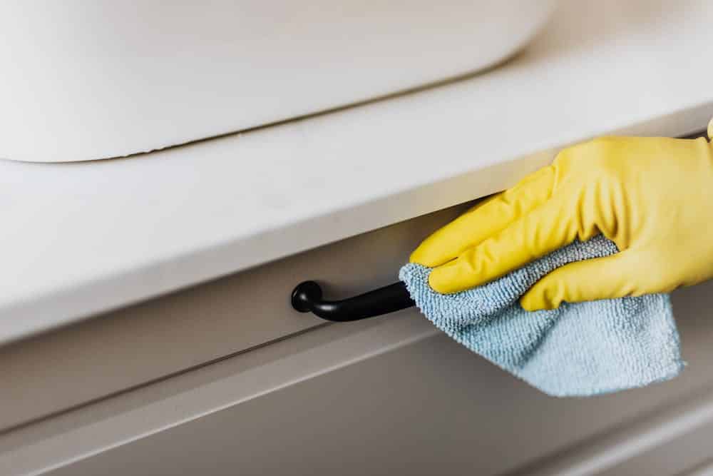 Image showing a gloved hand cleaning a kitchen cabinet